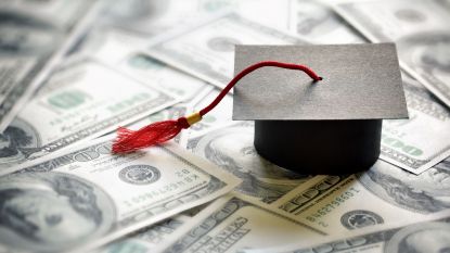 A graduation cap on a pile of hundred dollar bills.